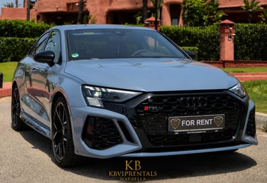 A light blue Audi RS3 luxury sedan for rent parked in front of a villa in Marbella, Spain.