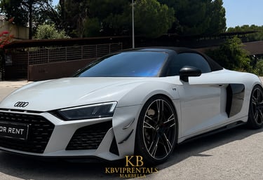 White Audi R8 Spyder luxury convertible for rent in Marbella, parked on a sunny street.