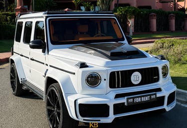 White Brabus Mercedes G-Wagon rental car parked outside a luxury villa in Marbella.