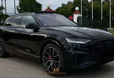 Black Audi Q8 luxury SUV rental parked on a stone driveway in Marbella.