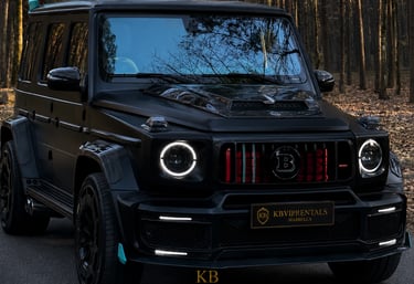 A customized matte black Brabus G-Wagon luxury SUV parked in a forest setting for high-end vehicle rentals.