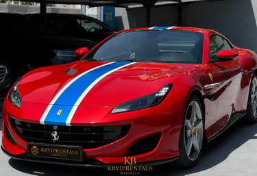 Red Ferrari Portofino luxury rental car with blue and white racing stripes parked in Marbella.