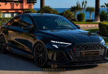 Black Audi RS3 luxury car rental in Marbella parked by the Mediterranean coast with ocean views.