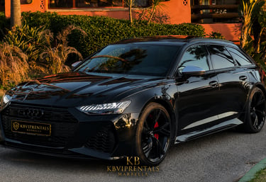 Sleek black Audi RS6 Avant luxury car rental parked in Marbella at sunset.