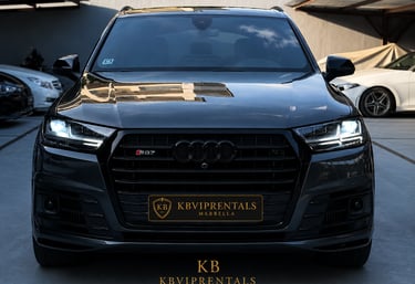 Front view of a black Audi SQ7 luxury SUV rental in Marbella with headlights on.