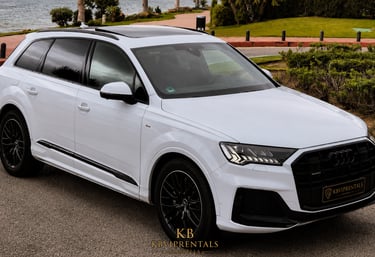 White Audi Q7 luxury SUV with black rims parked on a scenic coastal road in Marbella.