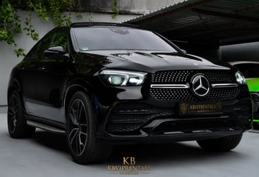Sleek black Mercedes-Benz GLE Coupe luxury SUV parked at a premium car rental showroom.