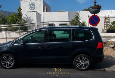Black Volkswagen Sharan luxury minivan rental parked at Baños Beach club in Marbella.