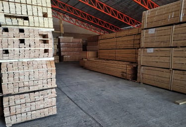Stacks of industrial lumber and wood planks stored in a large warehouse facility.