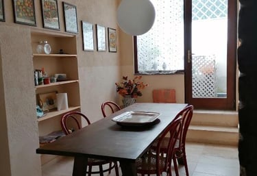 Rustic dining room with a dark wood table, red chairs, and a globe pendant light near a balcony door.