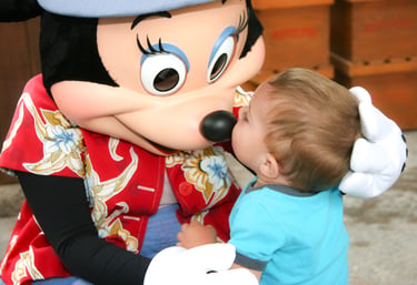 A toddler kisses Minnie Mouse's nose during a Disney vacation character meet and greet.