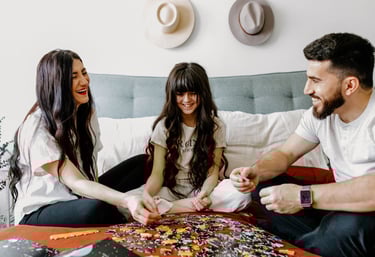 Mom, Dad, and daughter are doing a puzzle together.