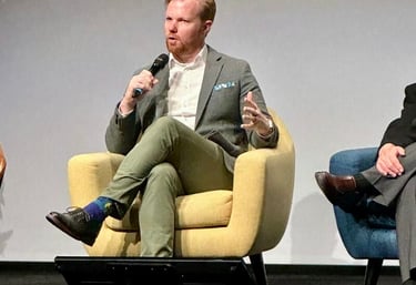 Nick Reese speaking on panel on emerging technology sitting in chair wearing green blazer
