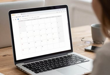 A neat workspace showing a laptop with a calendar and emails on screen.
