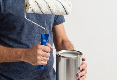 A painter carefully applying bright blue paint on a modern interior wall.