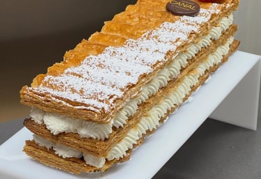 Gourmet mille-feuille pastry with layers of flaky puff pastry, whipped cream, and a fresh raspberry.