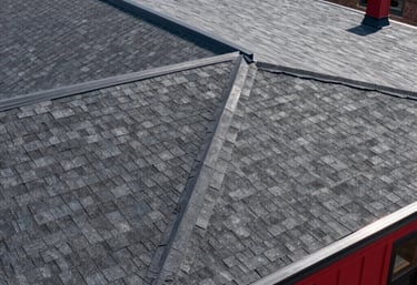 Top-down view of a completed high-durability residential roof in New York City with clean structural lines, dark gray shingles, and architectural red accents.