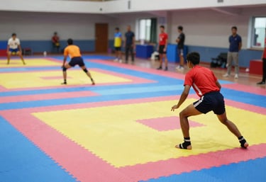 A wide shot of a training session where young athletes are practicing Kabaddi techniques on professional mats. The environment is vibrant and dynamic.