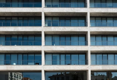Minimalist architectural detail of a modern Spanish office building with clean lines and blue glass windows under bright sunlight.