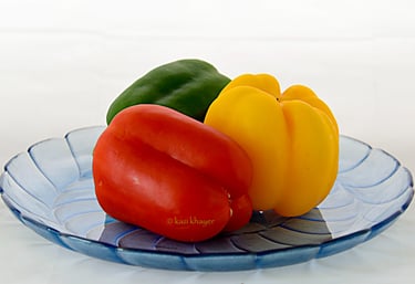Picture of bell pepper—green red and yellow—placed on a glass plate.