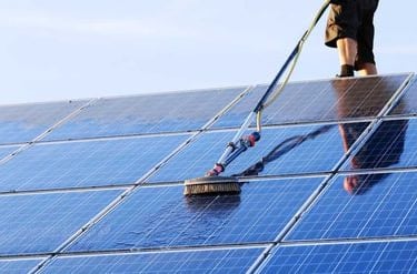 a man cleaning a solar paneled roof of a solar paneled house