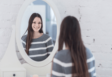Mujer joven contemplándose al espejo. Se nota contenta consigo misma, buena autoestima.