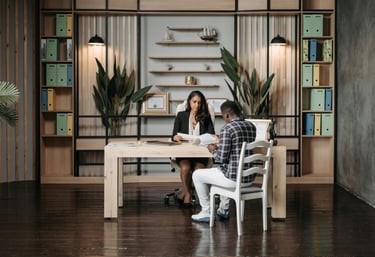 a man and woman sitting at a table with a laptop