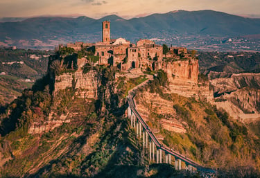 Panoramic view of the ancient hilltop village of Civita di Bagnoregio in Italy connected by a long pedestrian bridge.