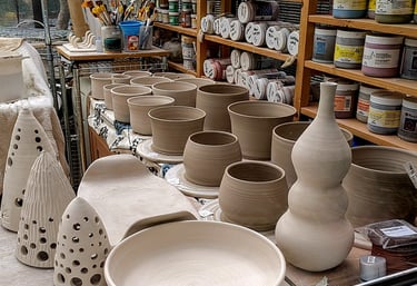 Pottery in production in the GonPotty studio with glazes and tools in the background
