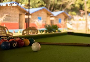 Pool table game at Jungle Lore Resort with cottages in background