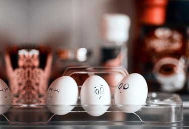 three eggs with faces drawn on them in a plastic container