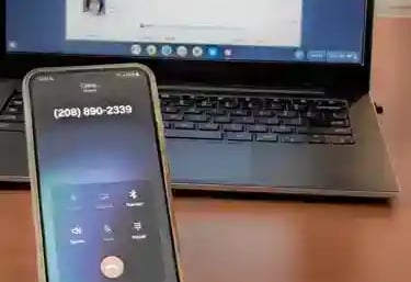 A smartphone displaying an active phone call to bail bondsman next to an open laptop.