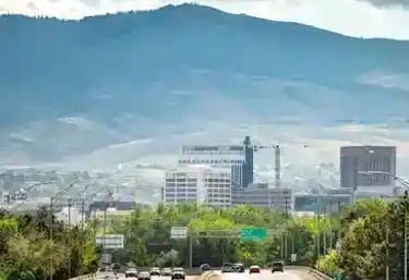 Aerial view of cars driving on a highway toward the Boise skyline with mountains in the background.