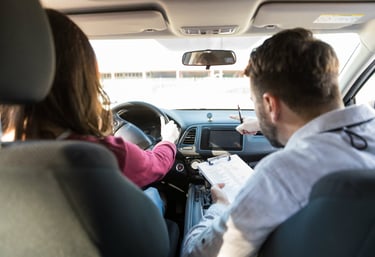 deux personnes dans une voiture dont un contrôleur avec un papier et stylo