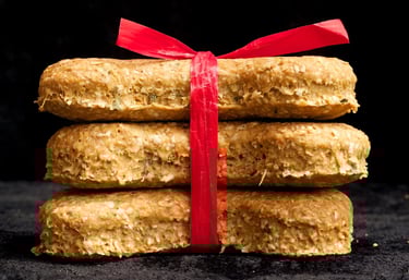 Stack of three homemade organic dog treats tied with a red ribbon against a black background.