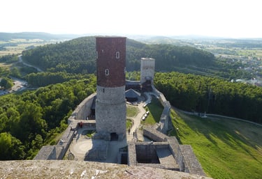 Widok z drona na zamek w Chęcinach. Środek lata. Dużo zielonego lasu w około.
