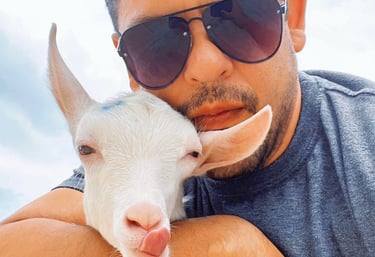 a man with sunglasses and sunglasses is holding a goat