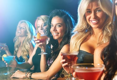 Group of women enjoying drinks at a VIP club crawl in Las Vegas, smiling and having fun at the bar.