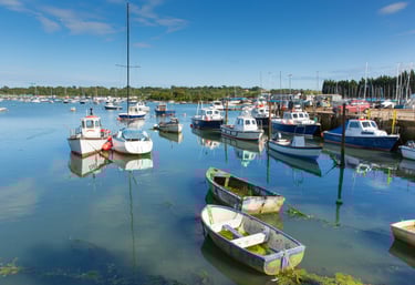 fishing boats floating in small estuary on a sunny day with blue skies