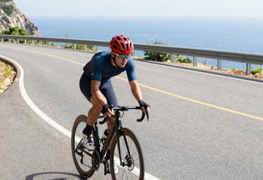 Road cyclist speeding along a coastal route with sea and hills in the background. avvicina il ciclis