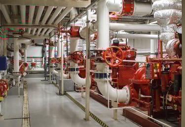 Cuarto de bombas contra incendios industrial con válvulas rojas y tuberías blancas para sistemas de