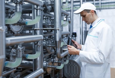 Ingeniero con bata de laboratorio blanca usando una tableta digital para monitorear tuberías industr