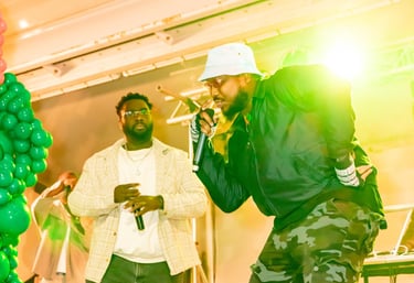 Musician in a white bucket hat and camo pants performing live on stage at Afro Fiesta Festival.