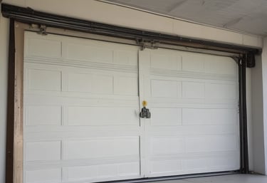 Technician repairing a modern garage door with professional tools on a sunny day.
