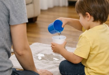 Child pouring water between two cups at home
