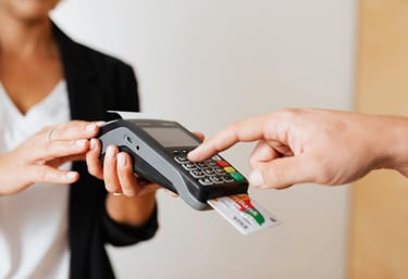 Customer entering PIN on a credit card terminal for a secure contactless payment transaction.