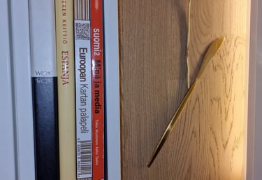 Finnish Wooden Map Puzzle on a shelf next to a decorative brass wall sculpture.