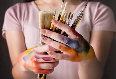 artista con pinceles y manos con pintura