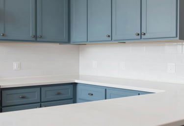 A bright, sparkling clean kitchen in a North American / US house with slate blue cabinetry and frost white countertops, showing zero pests.