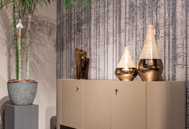 Modern luxury sideboard with decorative gold vases and a tall potted palm plant against textured wallpaper.